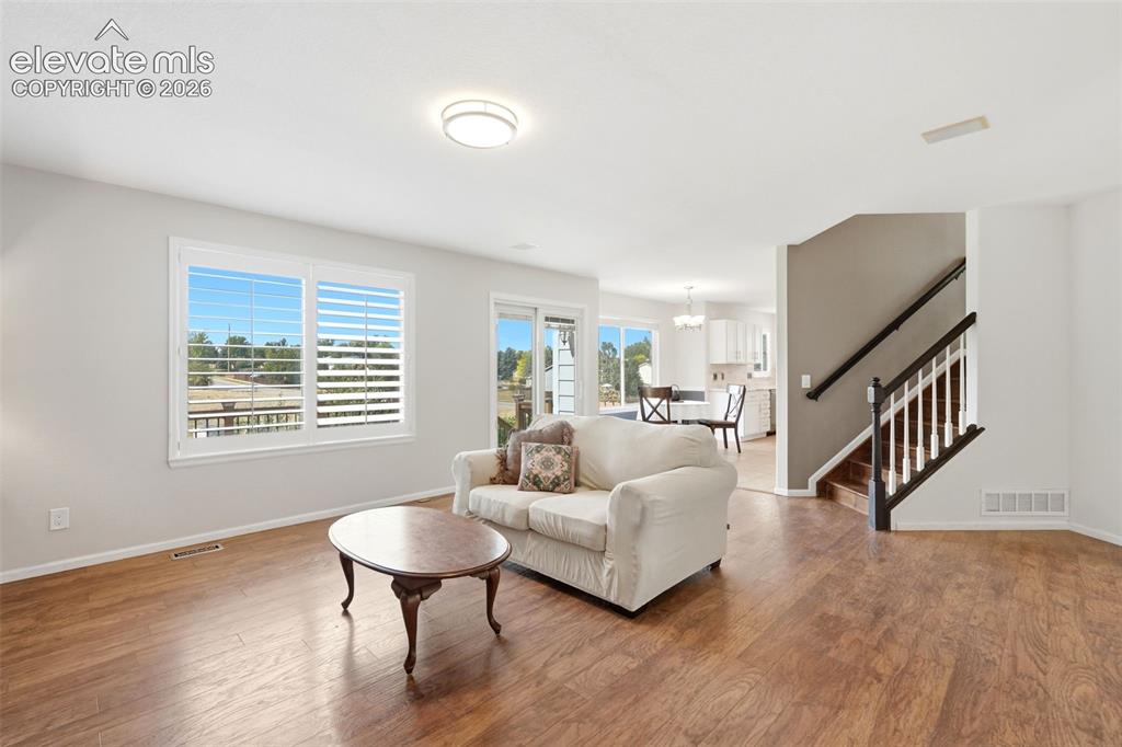 Image 13 of 43: Living area featuring wood-finish flooring, white plantation shutters, a co