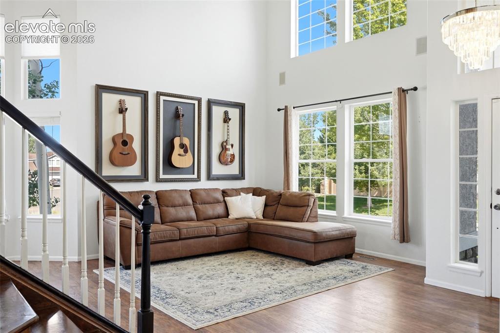 Image 14 of 43: Two-story living area featuring tall windows, upper transom windows, wood-f