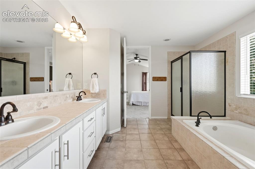 Image 22 of 43: Spacious bathroom featuring a dual vanity with white cabinetry and tiled co