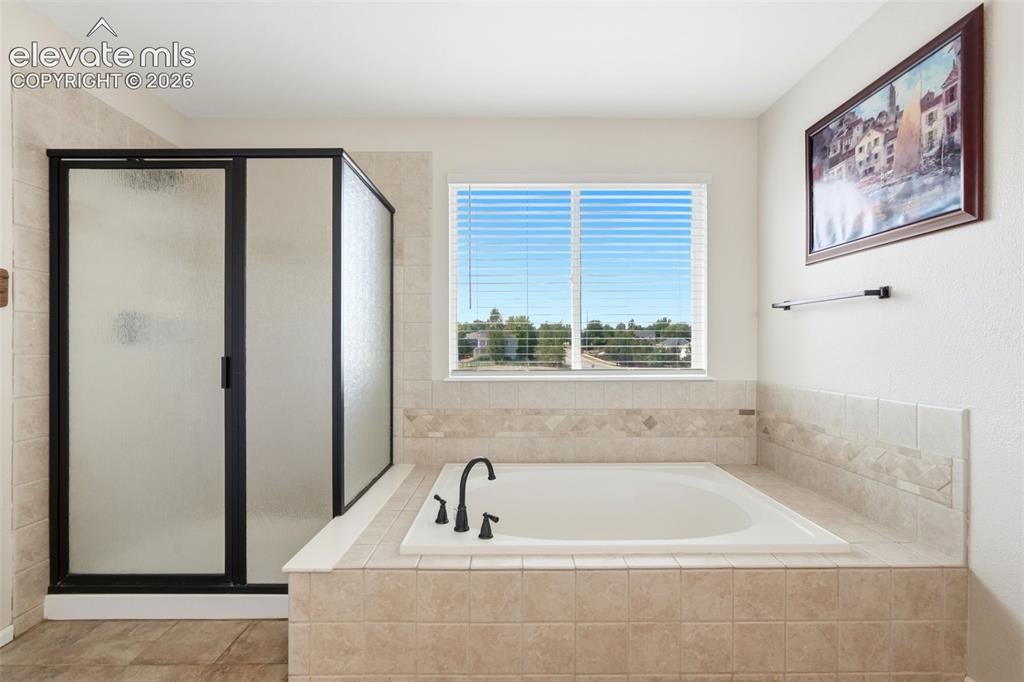 Image 23 of 43: Soaking tub with matte black fixtures, surrounded by light-toned tile