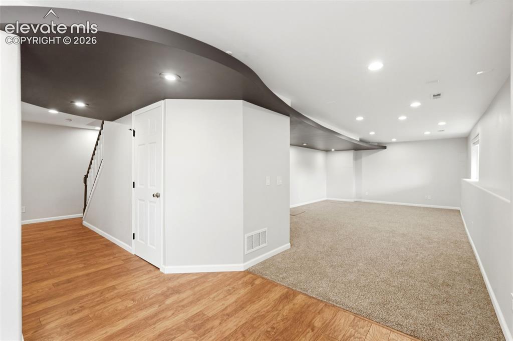 Image 34 of 43: Expansive lower-level space featuring a contemporary curved ceiling design