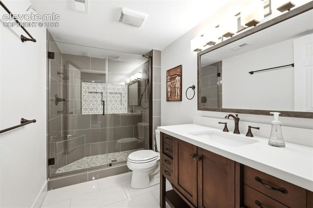 Image 37 of 43: Bathroom featuring a wood-finish vanity with a white countertop and undermo