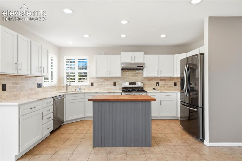 Image 7 of 43: Kitchen featuring light tile flooring, white cabinetry, a central island wi