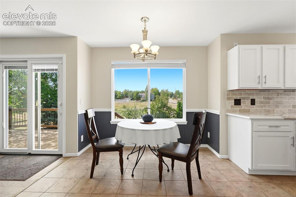 Image 9 of 43: Bright eat-in kitchen area featuring tile flooring, white cabinetry, a ston