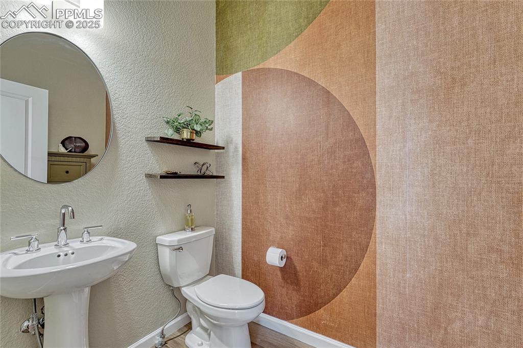 Image 18 of 50: Just past the stairs is a large half bath/powder room with a stylistic wall