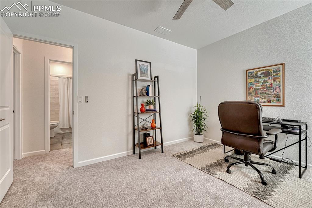 Image 34 of 50: Across the upper level hall bath is a third bedroom with ceiling fan
