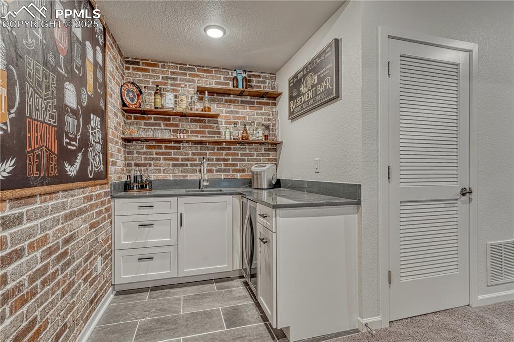 Image 38 of 50: The Chicago-style wet bar features grey quartz countertops and built-in win