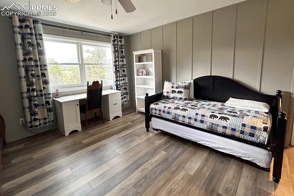Image 19 of 50: Bedroom featuring a ceiling fan, dark wood-style flooring, and a decorative