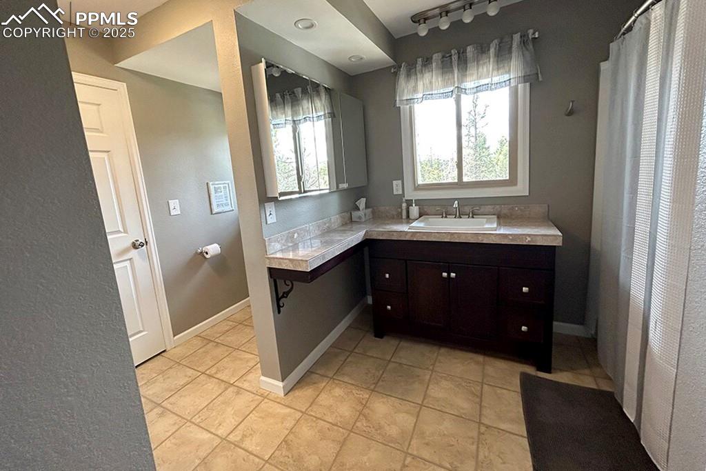 Image 21 of 50: Bathroom with vanity, a textured wall, light tile patterned floors, and rai