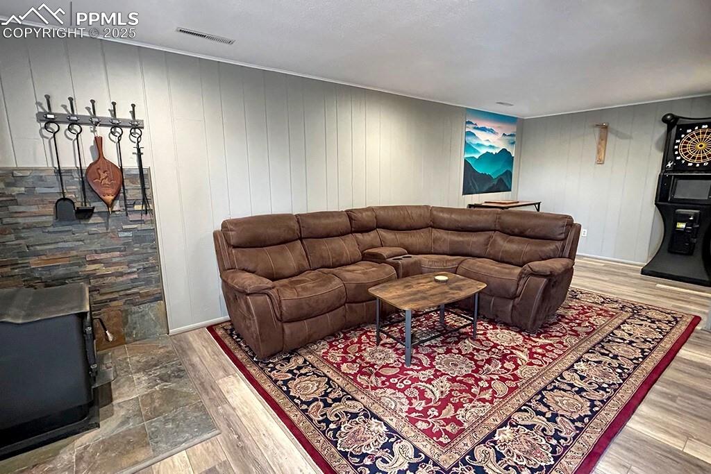 Image 23 of 50: Basement family area featuring a wood stove, light wood-style flooring, and