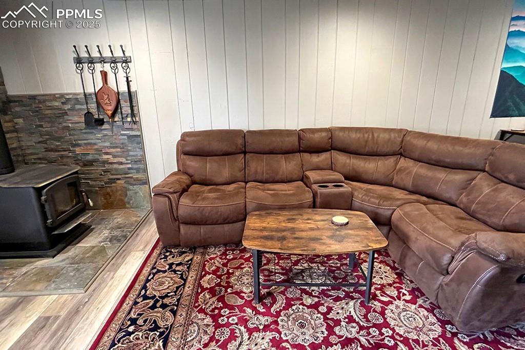 Image 24 of 50: Basement family room featuring a wood stove, wood finished floors, and wood