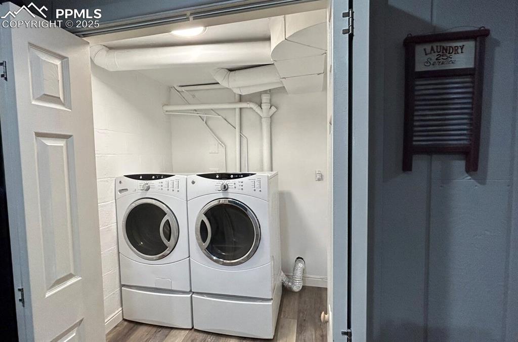 Image 25 of 50: Washroom featuring wood finished floors, washer and clothes dryer