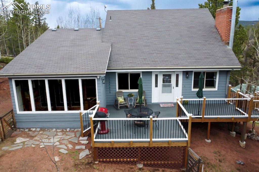 Image 31 of 50: Back of house with a patio, a wooden deck, an outdoor fire pit, and a chimn
