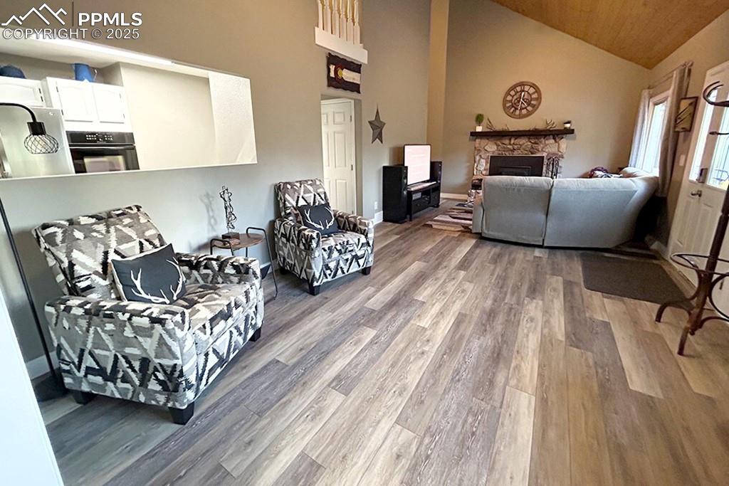 Image 6 of 50: Living area featuring a fireplace, high vaulted ceiling, and light wood-typ