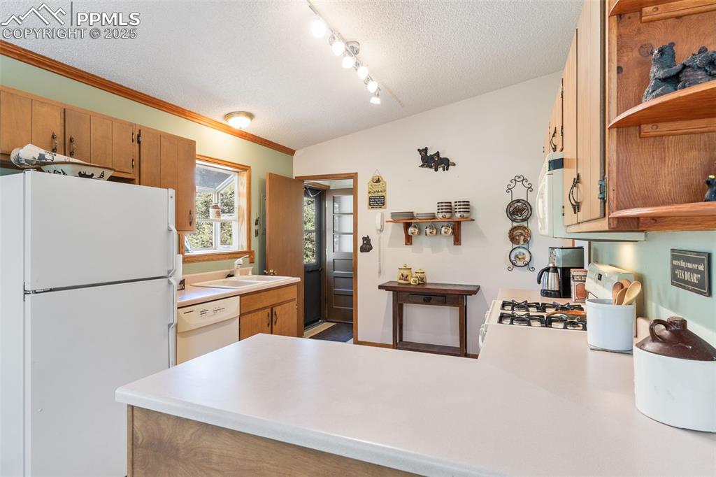 Image 10 of 35: Kitchen with open shelves, white appliances, light countertops, a peninsula