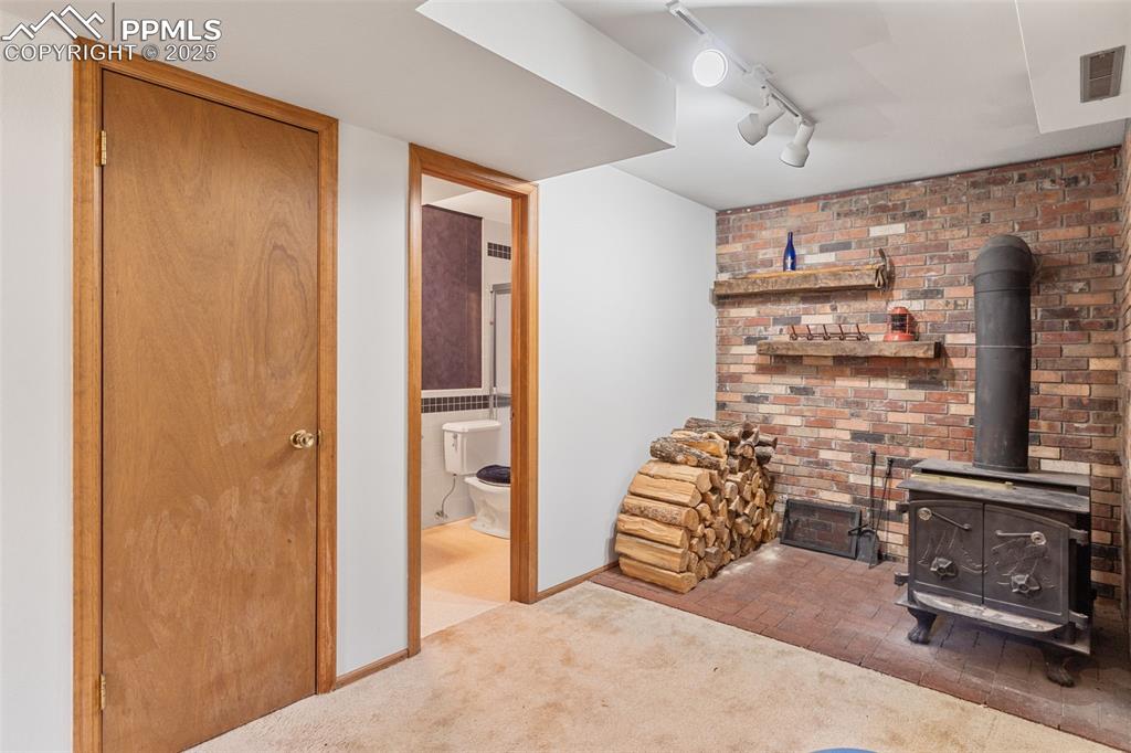 Image 26 of 35: Carpeted living area featuring a wood stove and rail lighting