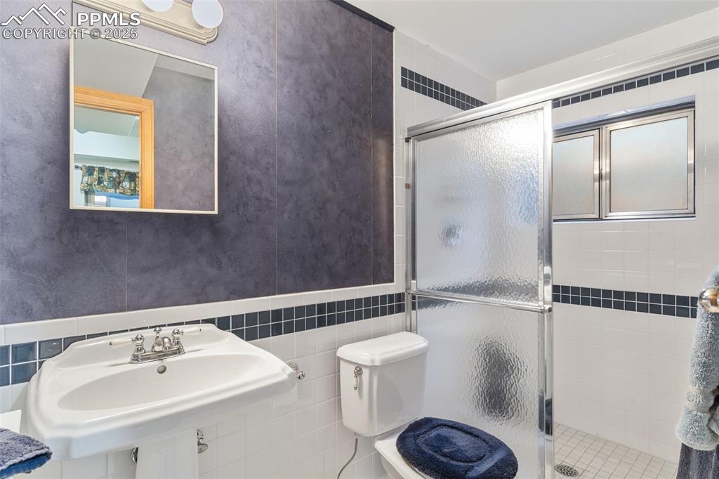 Image 28 of 35: Full bathroom featuring a shower stall and tile walls