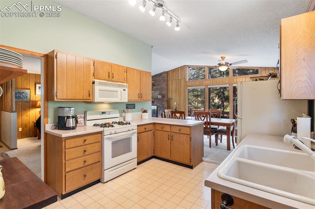 Image 8 of 35: Kitchen with white appliances, vaulted ceiling, a peninsula, a textured cei