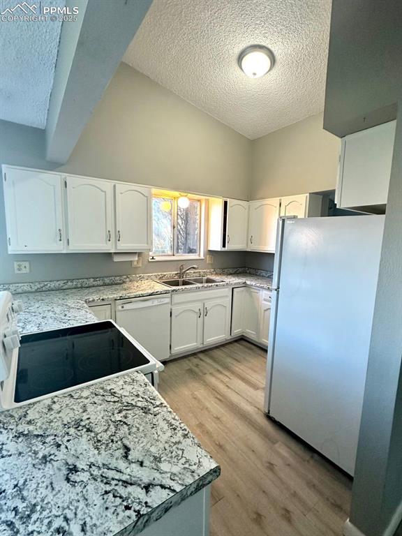 Image 4 of 13: Kitchen featuring white cabinetry, a textured ceiling, sink, white applianc