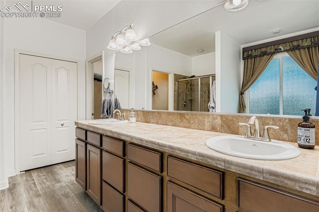 Image 14 of 28: Bathroom with a closet, a stall shower, double vanity, and light wood finis