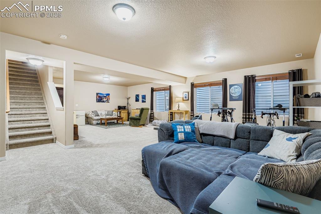 Image 20 of 28: Carpeted living room with a textured ceiling and stairs
