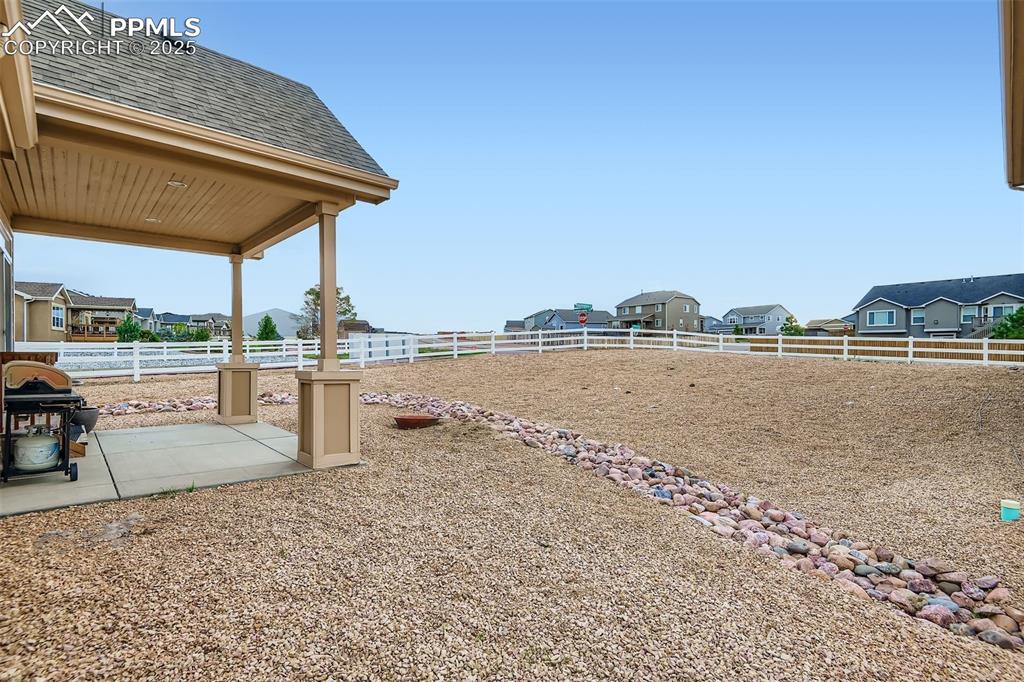 Image 26 of 28: Fenced backyard with a covered patio
