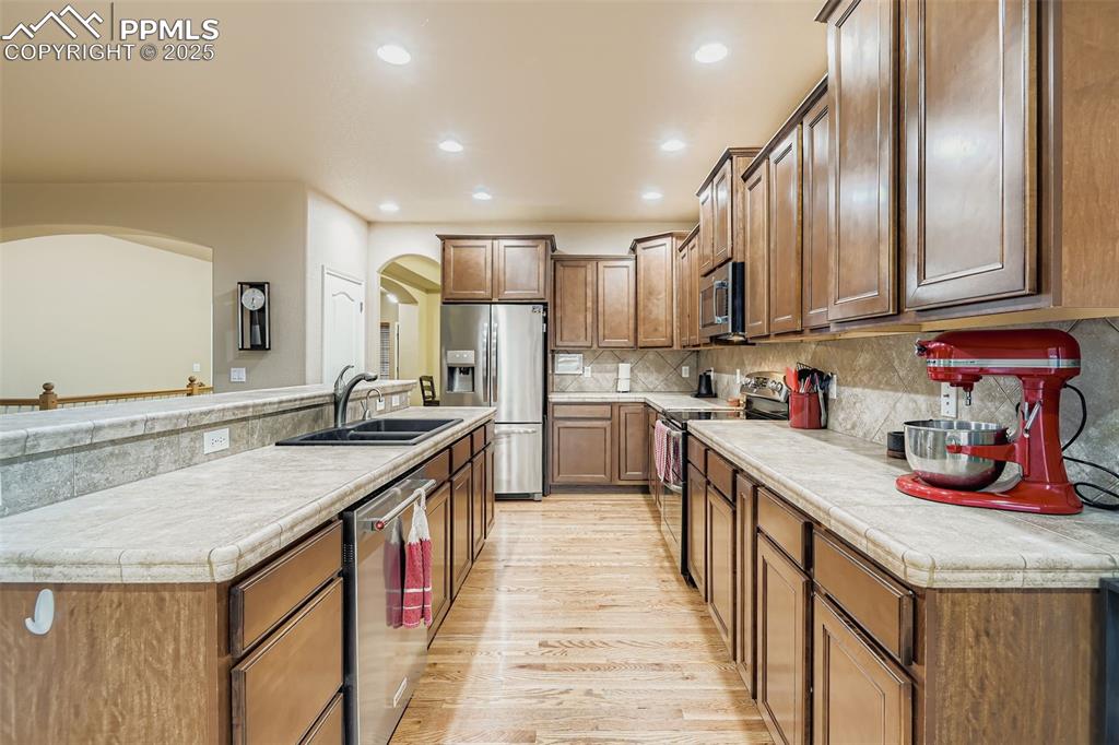 Image 8 of 28: Kitchen with stainless steel appliances, wood floors, decorative backsplash
