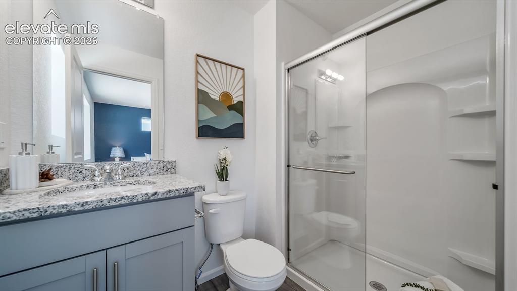 Image 21 of 26: Bathroom featuring a single vanity with a speckled countertop, a mirrored m