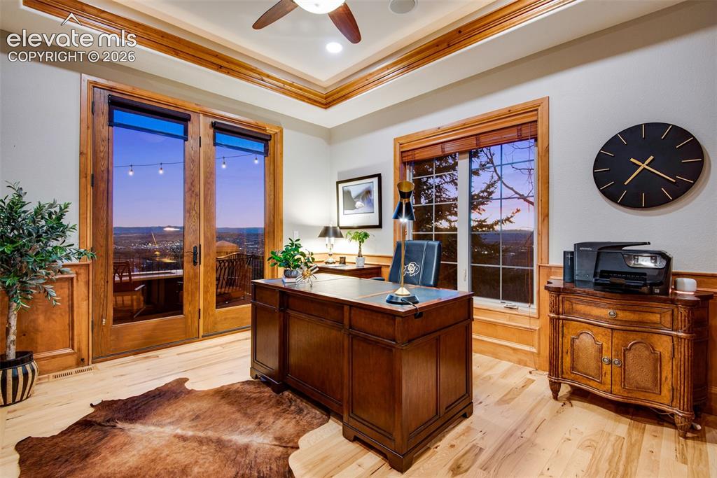 Image 27 of 50: French doors lead you into an executive office featuring a gas fireplace wi