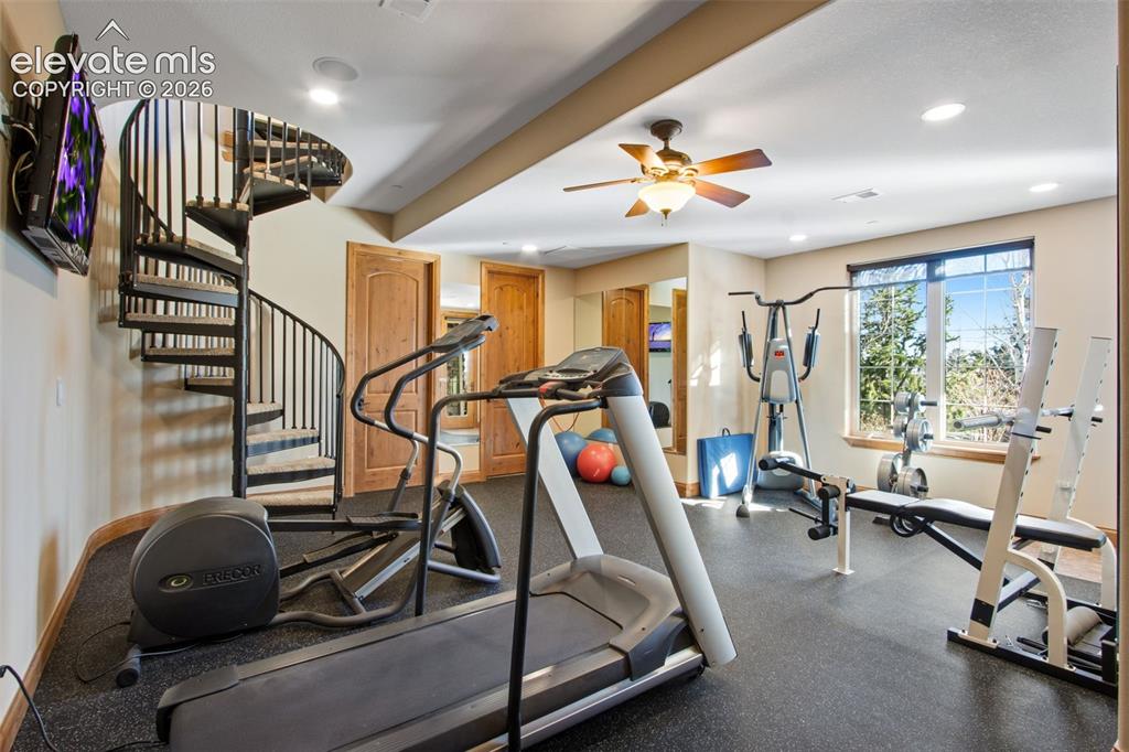 Image 32 of 50: Gym with ceiling fan, TV, patio access, rubber flooring and mirrors include