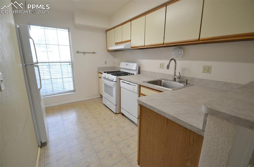 Image 10 of 31: Kitchen featuring white appliances, light countertops, and under cabinet ra