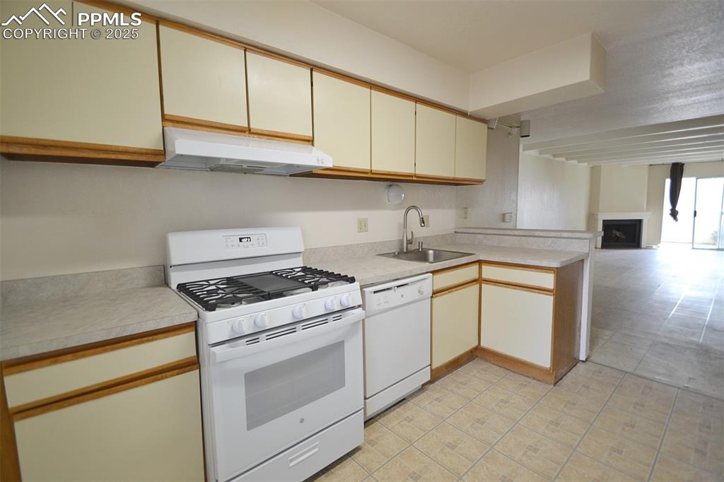 Image 11 of 31: Kitchen featuring white appliances, light countertops, a fireplace, under c