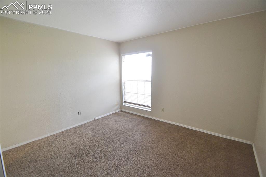 Image 16 of 31: Unfurnished room featuring dark colored carpet and baseboards