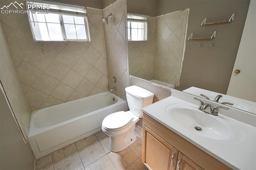 Image 24 of 31: Full bath with washtub / shower combination, vanity, and light tile pattern