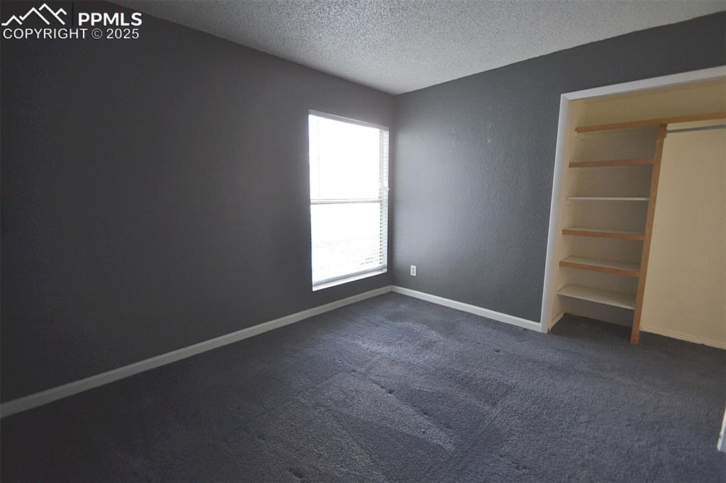 Image 26 of 31: Unfurnished bedroom featuring a textured ceiling and dark carpet