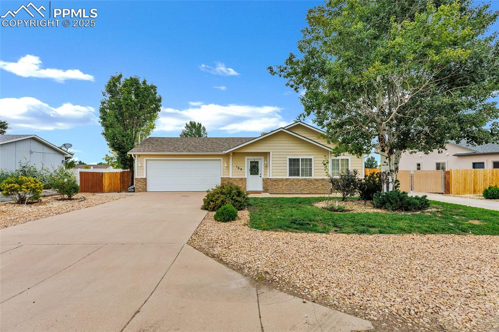 Caption: Ranch-style house with an attached garage, driveway, a shingled roof, and stone siding