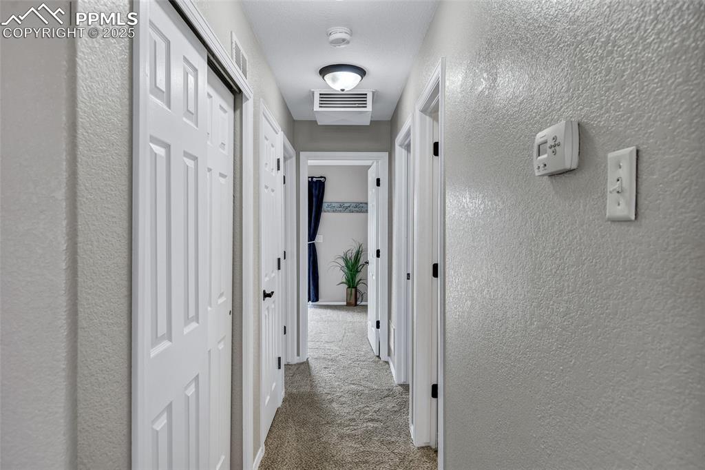 Image 10 of 39: Hallway to bedrooms and slider access to more entertaining outdoor areas