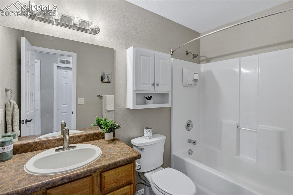 Image 13 of 39: Full bathroom with a textured wall, bathtub / shower combination, and vanit