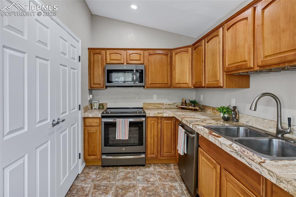 Image 9 of 39: Laundry behind 6 panel doors upper shelving doubles as a pantry in modern k
