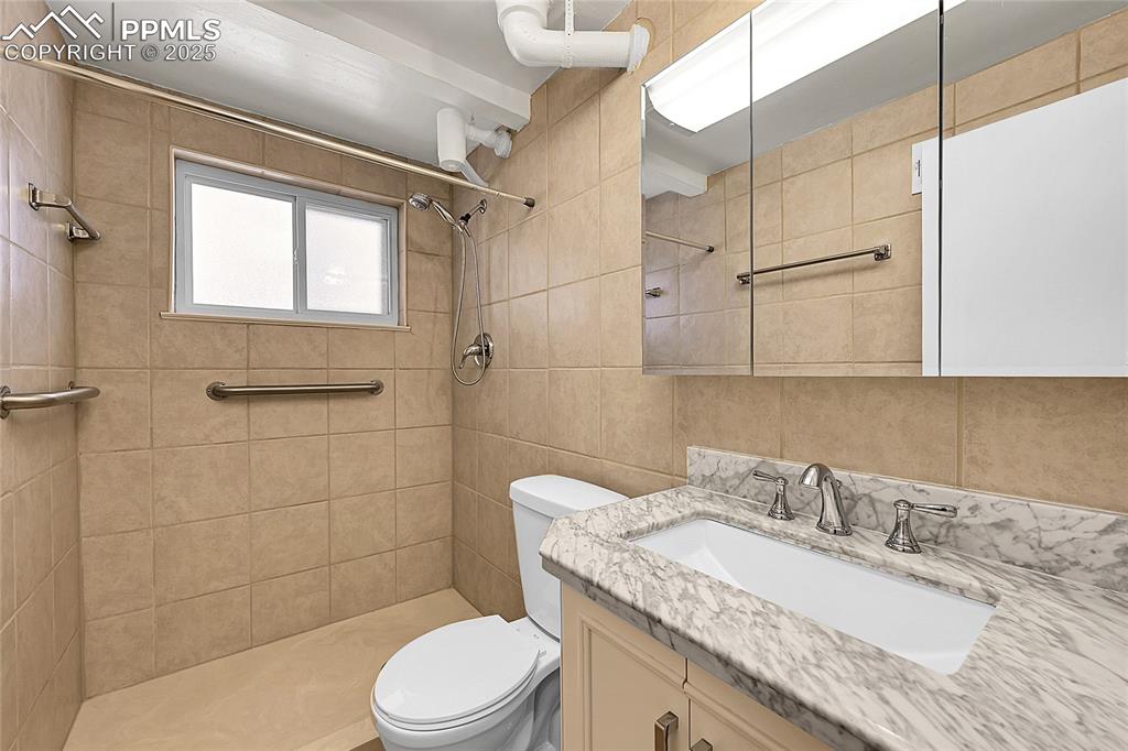 Image 13 of 27: Full bathroom with vanity, tiled shower, and tile walls