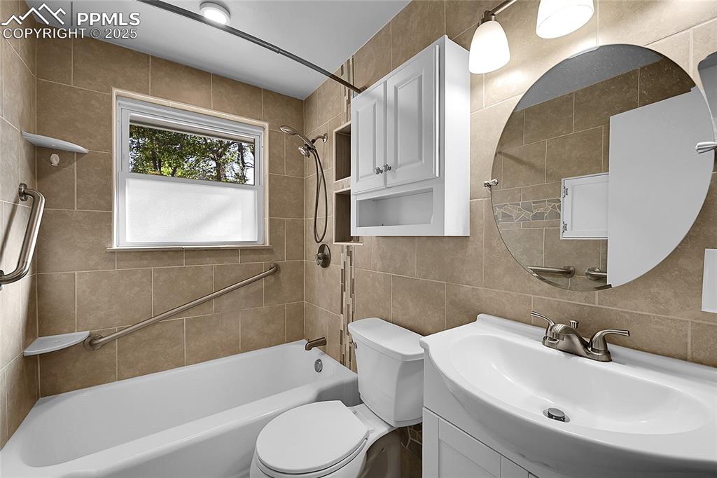 Image 14 of 27: Full bath with vanity, tile walls, and bathtub / shower combination