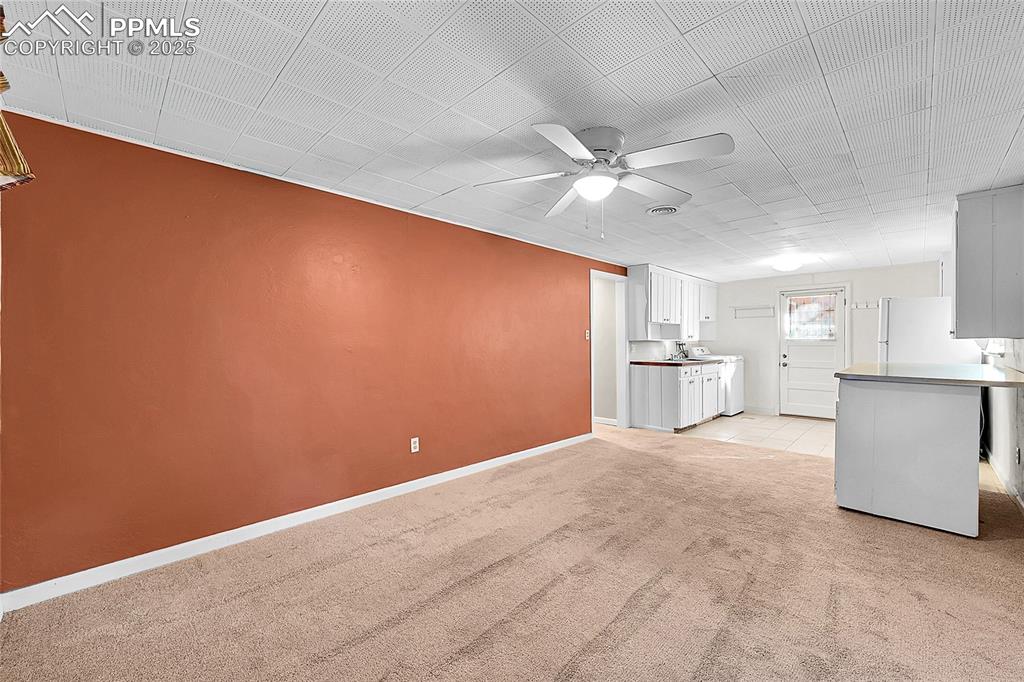 Image 18 of 27: Unfurnished living room featuring light colored carpet and a ceiling fan