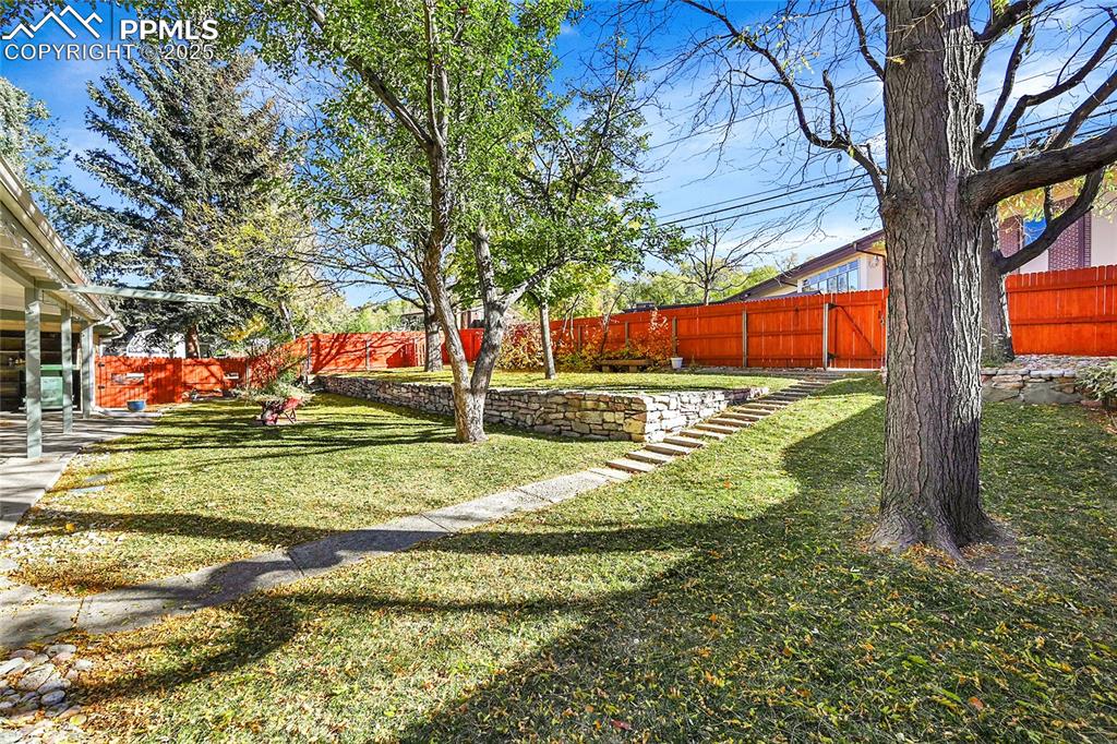 Image 22 of 27: Fenced backyard with a patio area