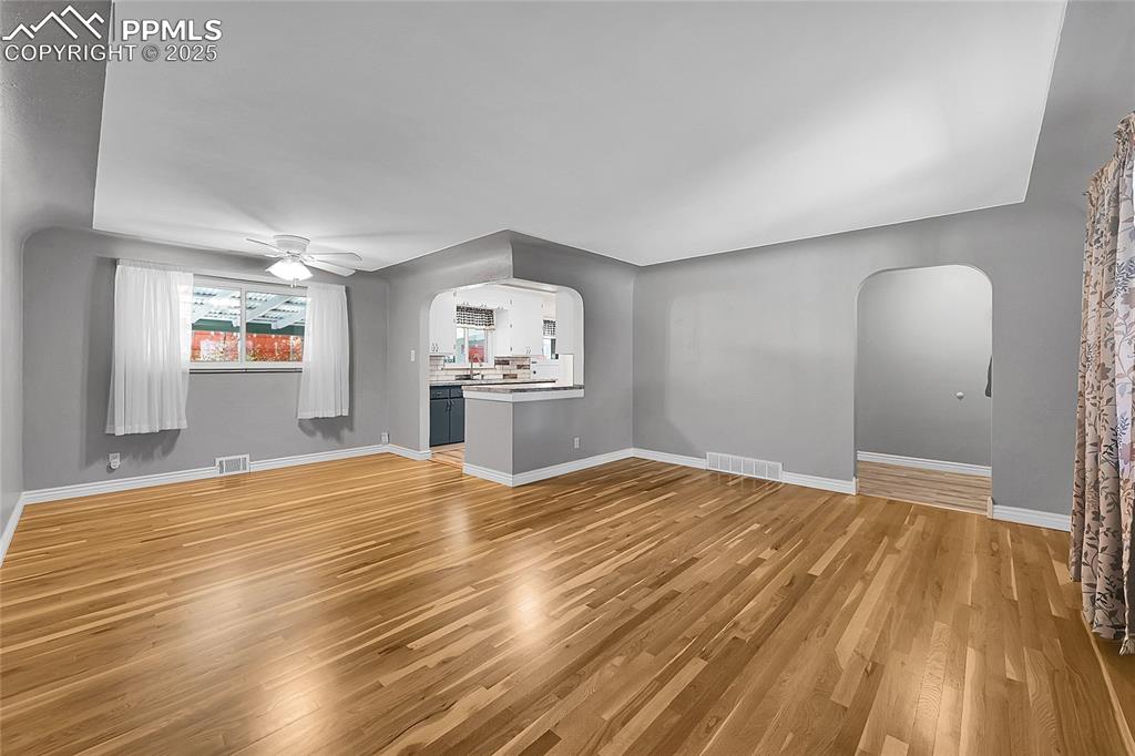 Image 3 of 27: Unfurnished living room with arched walkways, light wood-style flooring, an