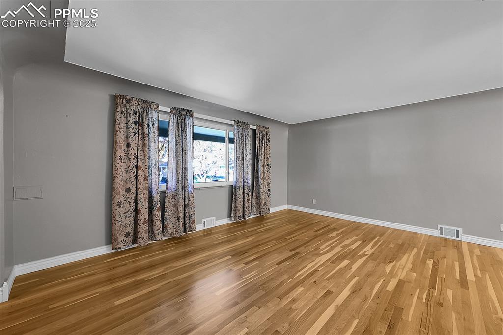Image 6 of 27: Unfurnished room with wood finished floors and baseboards