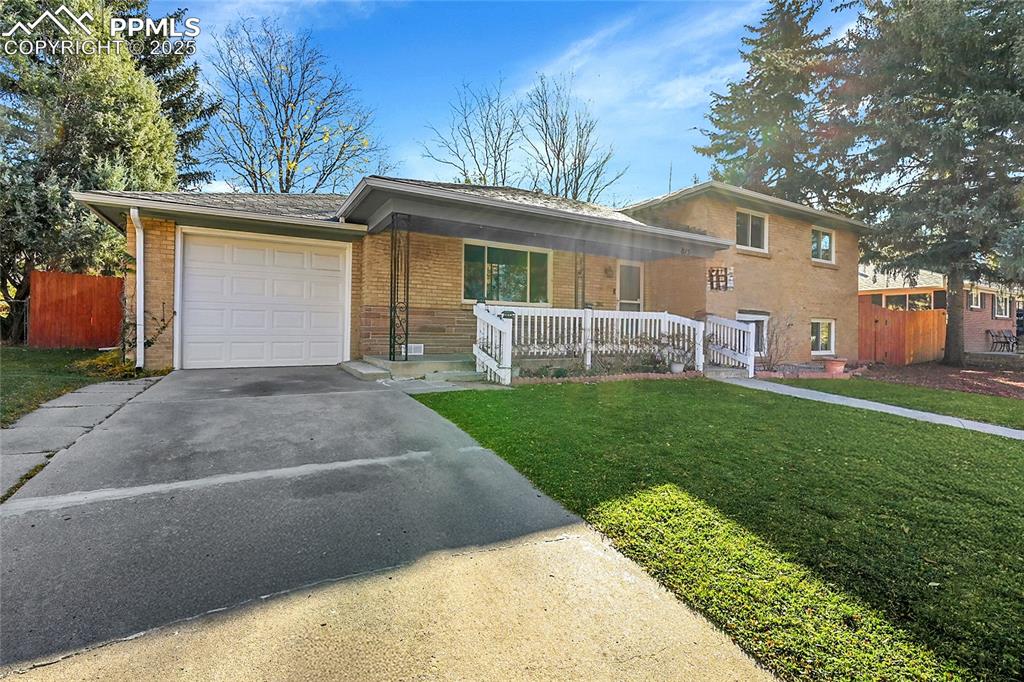 Image 7 of 27: Tri-level home featuring brick siding, concrete driveway, and an attached g