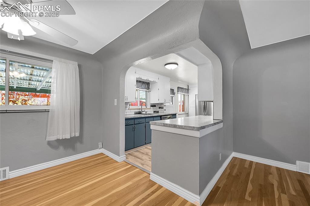 Image 8 of 27: Kitchen featuring arched walkways, light wood-style flooring, light counter