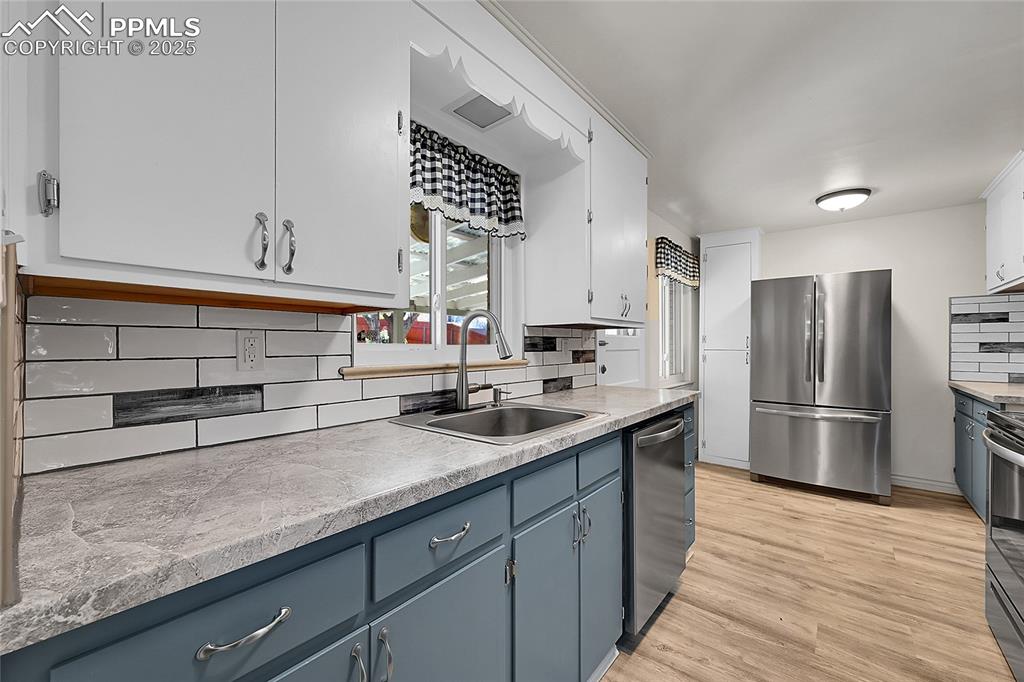 Image 9 of 27: Kitchen featuring backsplash, white cabinetry, light countertops, and stain