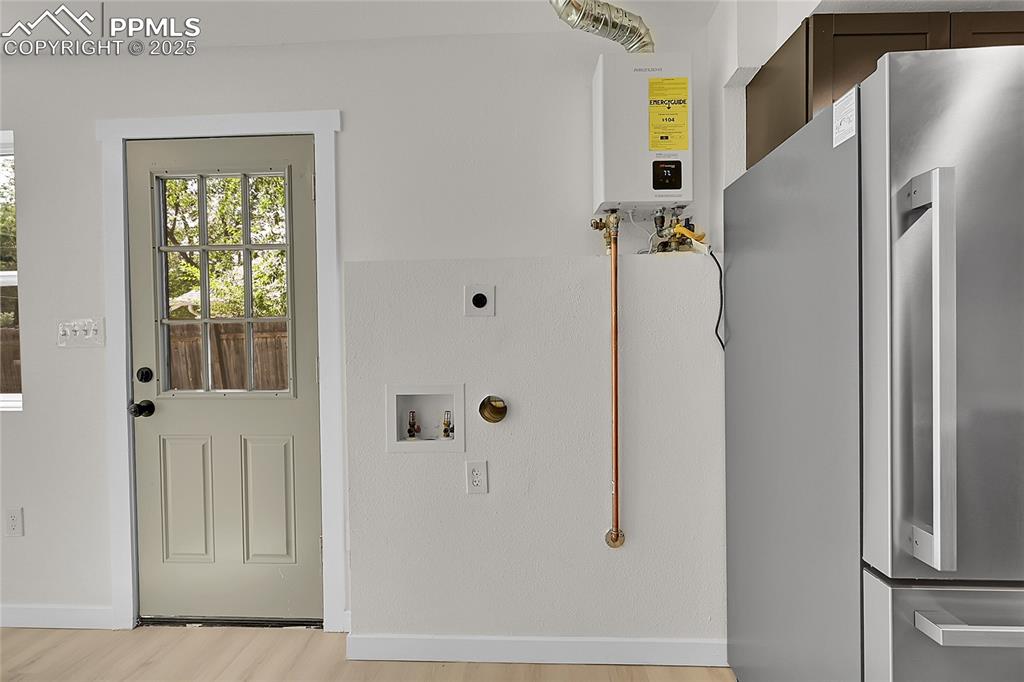 Image 10 of 29: Washroom featuring light wood finished floors, tankless water heater, gas d