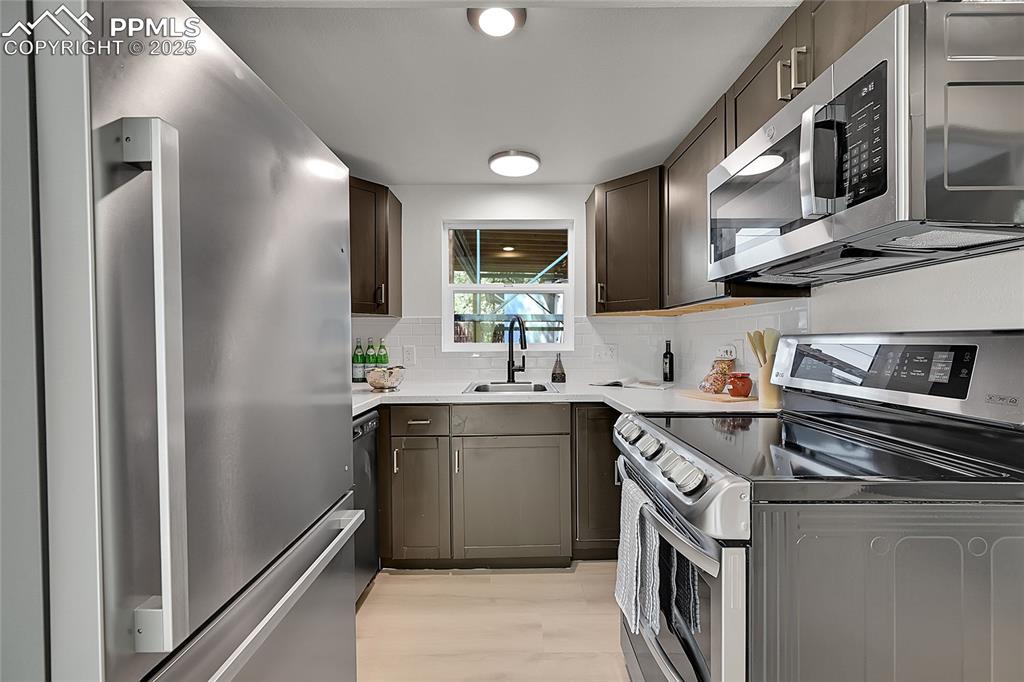 Image 11 of 29: Kitchen featuring stainless steel appliances, tasteful backsplash, light wo